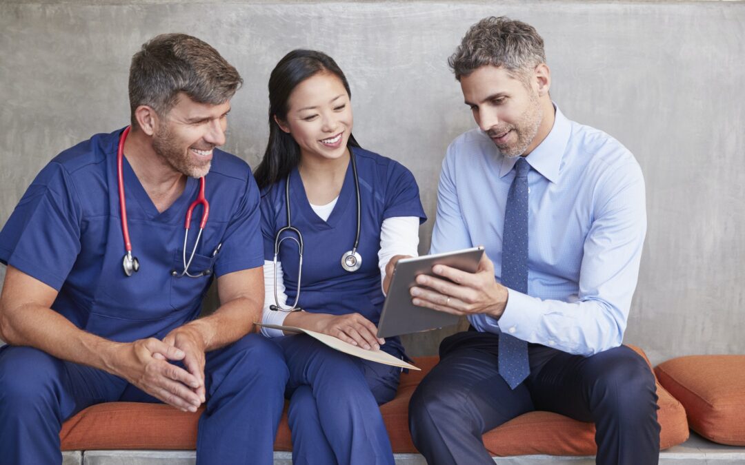Three healthcare workers sit using tablet computer together