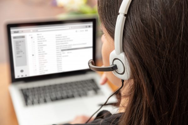 Home office, customer support, help desk concept. Woman with headset work on a laptop